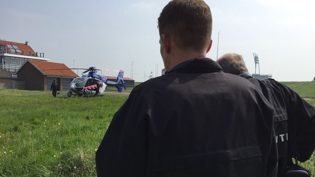 Politie-medewerkers kijken toe hoe de helikopter opstijgt