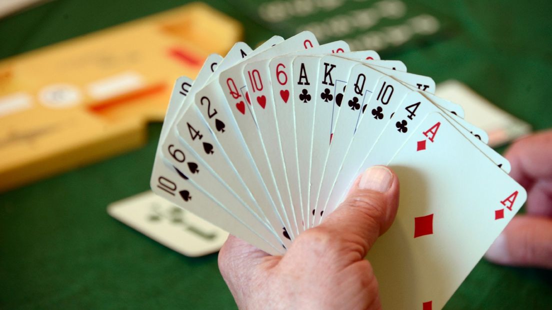 Een vrouw houdt een waaier kaarten in haar hand tijdens een spel bridgen