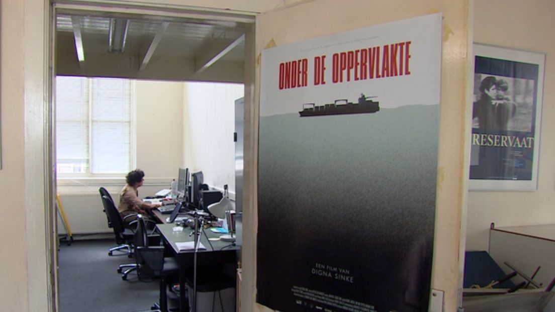 Documentairemaakster Digna Sinke monteert naast poster Onder de oppervlakte