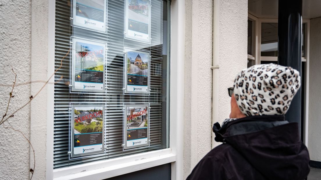 Een vrouw kijkt in Delfzijl bij een NVM-makelaar naar te koop staande woningen