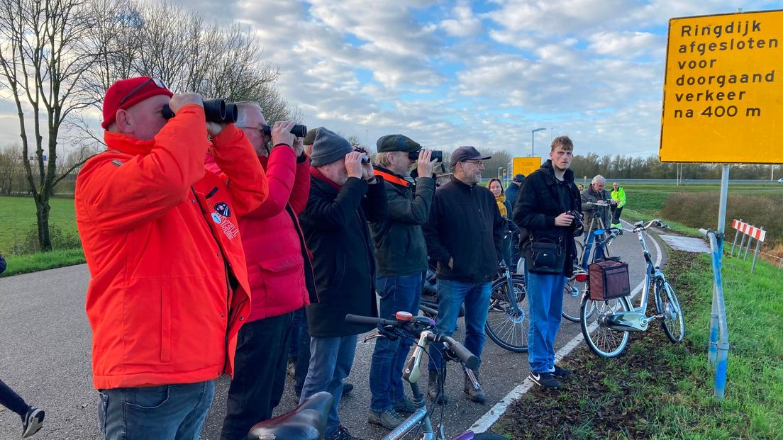 "Daar gáát ze", wordt er langs de Lekdijk in Vianen gezongen. Een clubje 'fans' heeft de verrekijkers in de aanslag om de operatie te volgen.