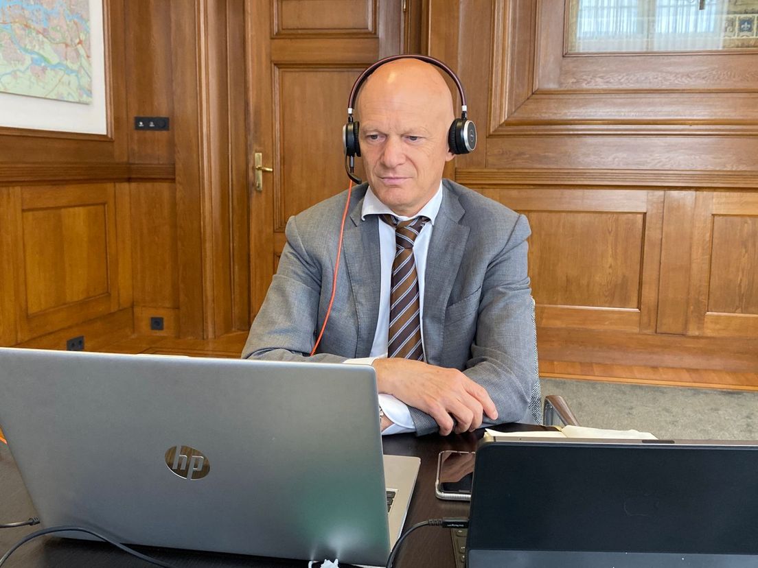 Vanwege corona vergadert de Rotterdamse gemeente online. Vanachter zijn laptop is wethouder Bert Wijbenga in debat met de raad.