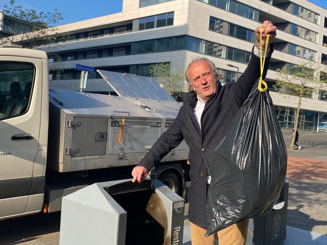 Leefbaar-raadslid Benvenido van Schaik met een vuilniszak naast de bak in de hand